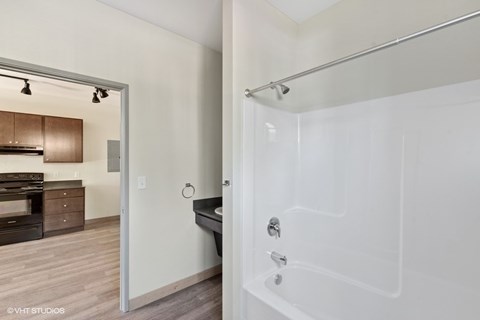 A white bathtub with a shower head attached to the wall.