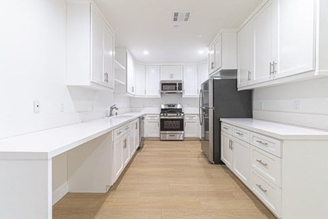 a large white kitchen with white cabinets and stainless steel appliances
