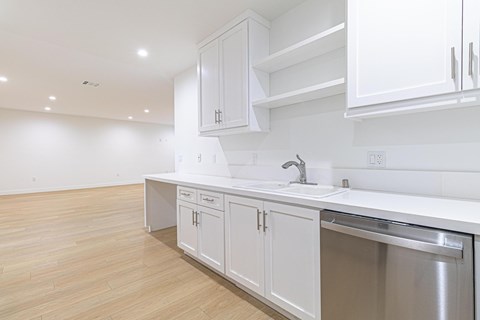 A kitchen with white cabinets and a stainless steel sink.