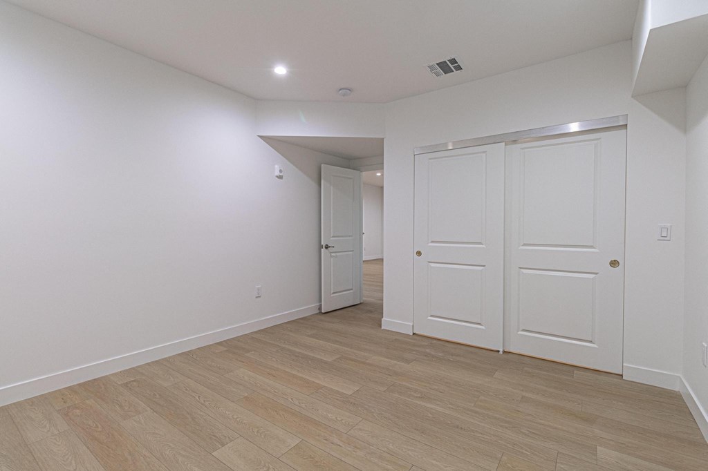 a living room and hallway with white walls and wood flooring