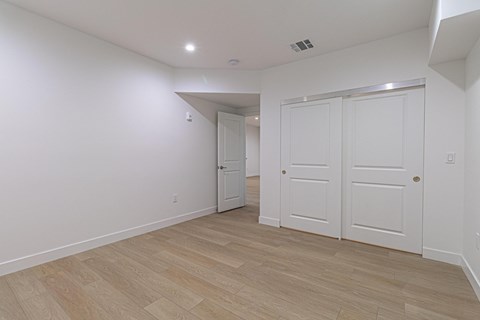 A room with white walls and wooden flooring with a door on the right.