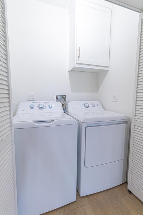 Two white front loading washing machines in a small laundry room.