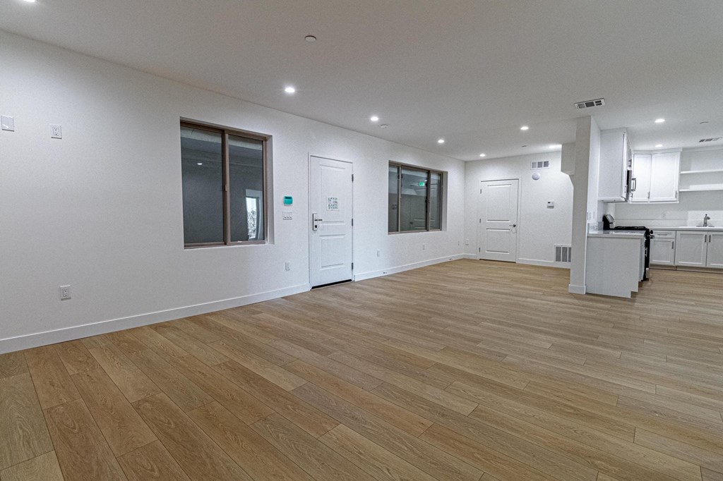 the living room and kitchen of a new home with white walls and wood floors
