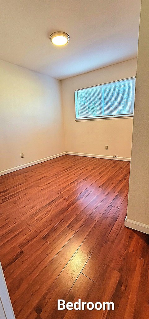 a bedroom with a hard wood floor and a window