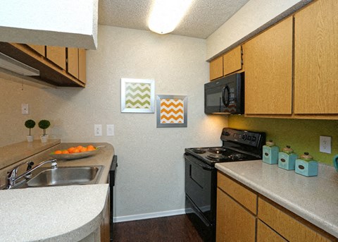 A kitchen with a black stove and wooden cabinets.