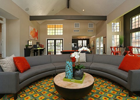 A living room with a grey couch and a coffee table with a vase of flowers on it.
