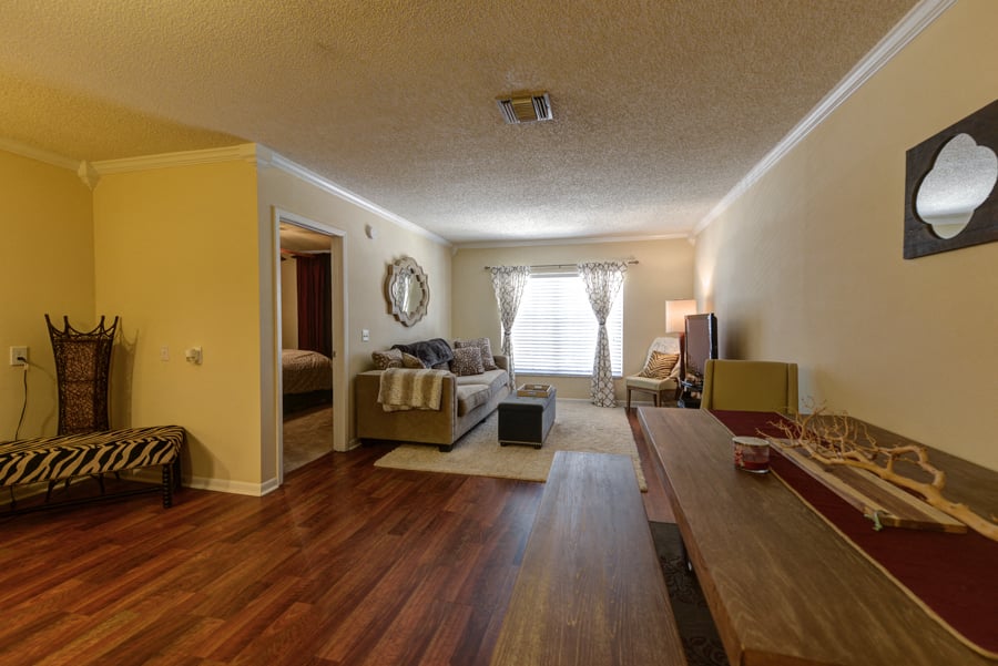 A living room with a brown wooden floor and a rug.