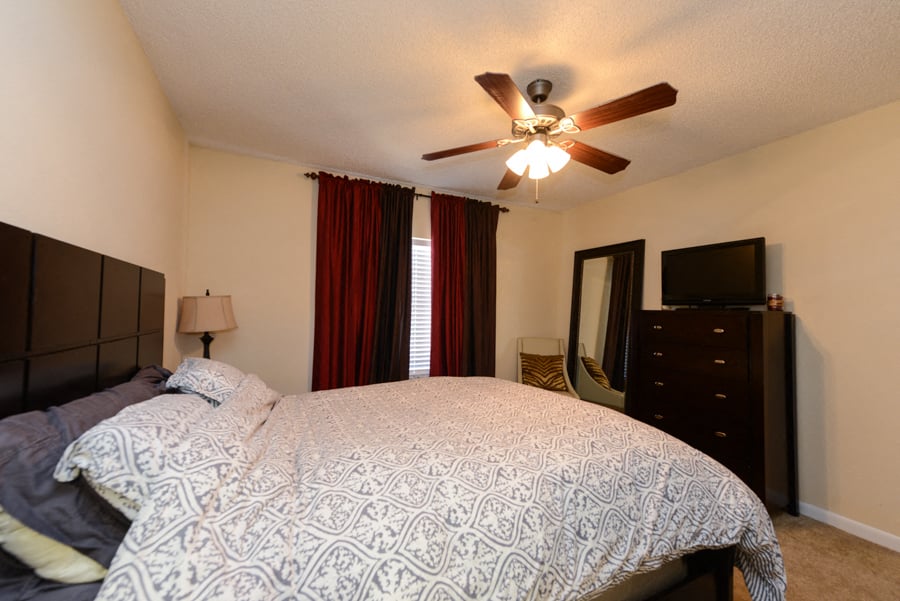 A bedroom with a bed, dresser, and television.