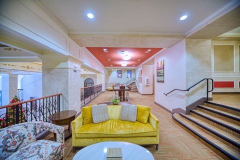 a living room with a yellow couch and a staircase