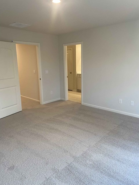 a living room with carpet and a door to a bathroom