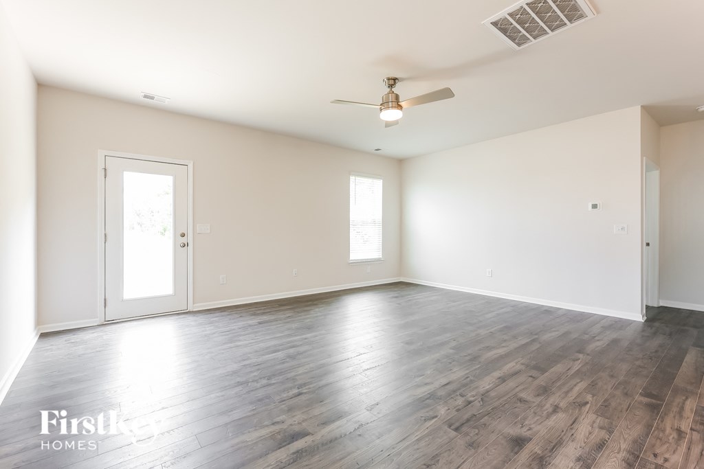 an empty living room with white walls and a ceiling fan