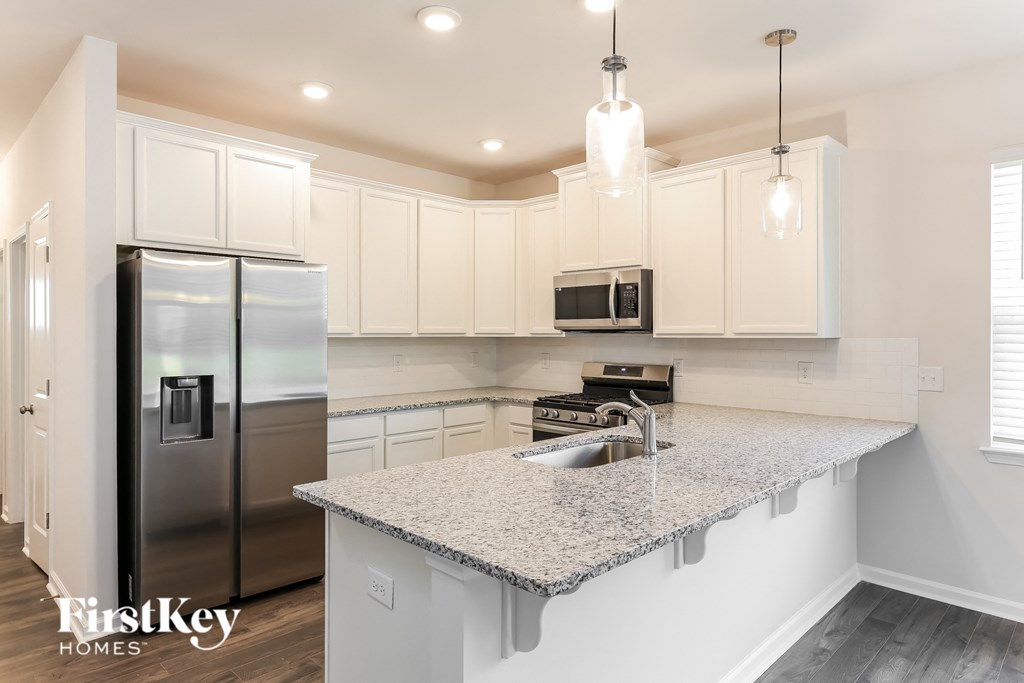 a white kitchen with granite counter tops and stainless steel appliances