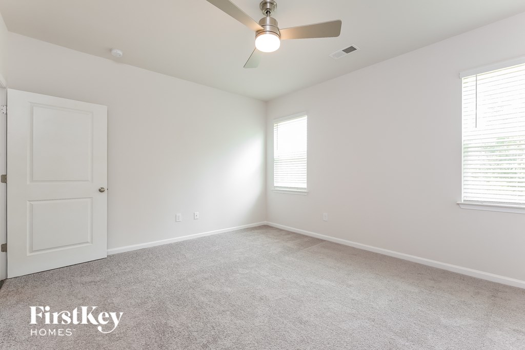 a bedroom with white walls and a ceiling fan and a white door