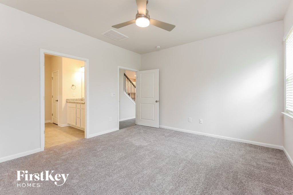 a spacious living room with carpet and a ceiling fan