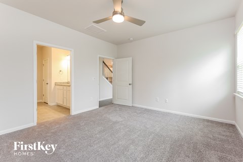 a spacious living room with carpet and a ceiling fan