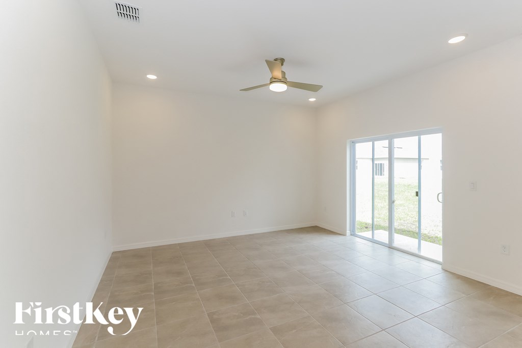 an empty living room with a ceiling fan and a window