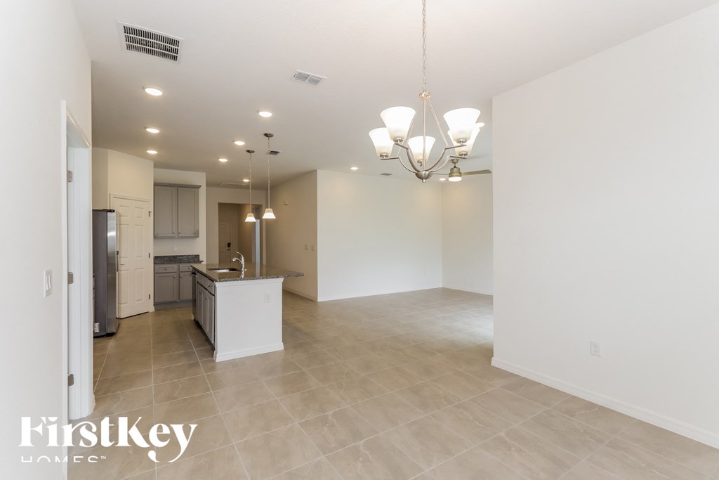 a kitchen and living room with white walls and tile flooring