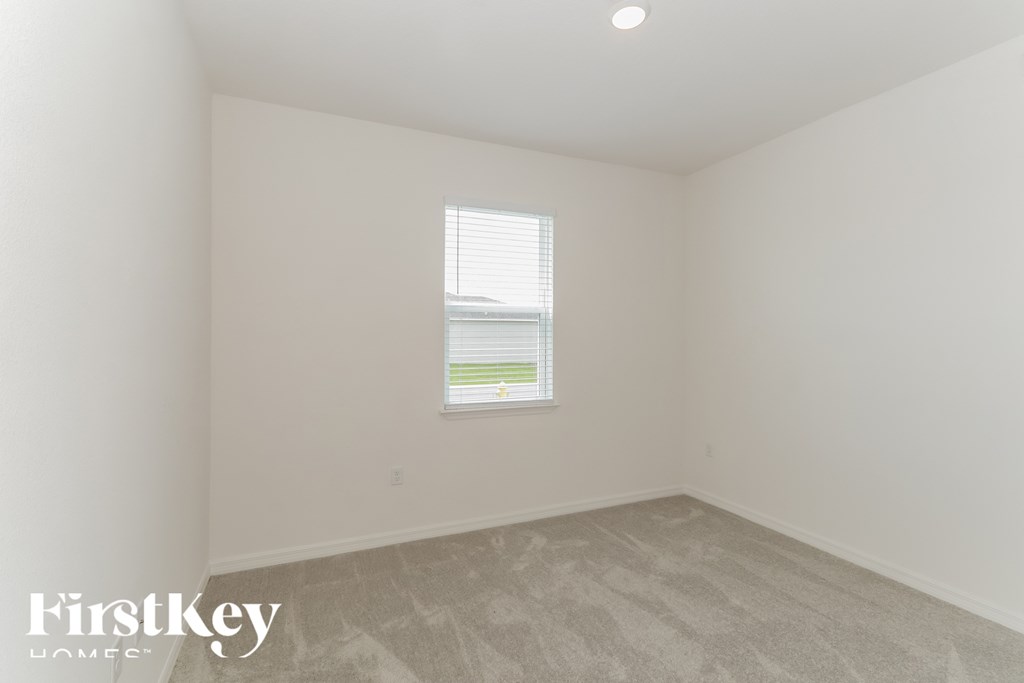 a bedroom with white walls and a window