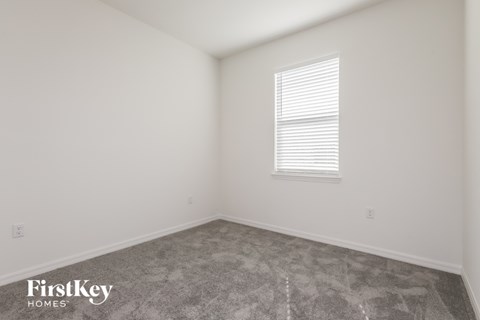 the living room of a home with white walls and a window