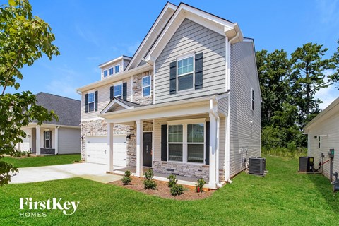 A house with a grey and white exterior and a large front yard.