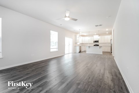A spacious room with wooden floors and a ceiling fan.