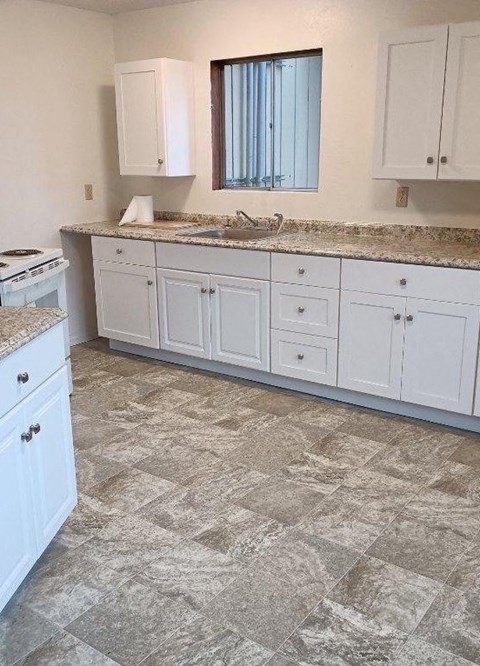 a kitchen with white cabinets and marble counter tops