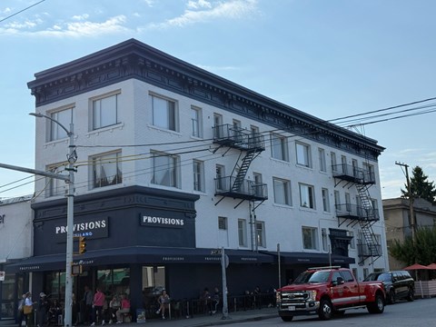 A white building with a black awning that says Provisions.