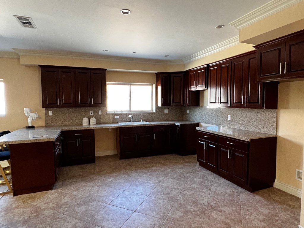 an empty kitchen with dark cabinets and tiled floors and a window