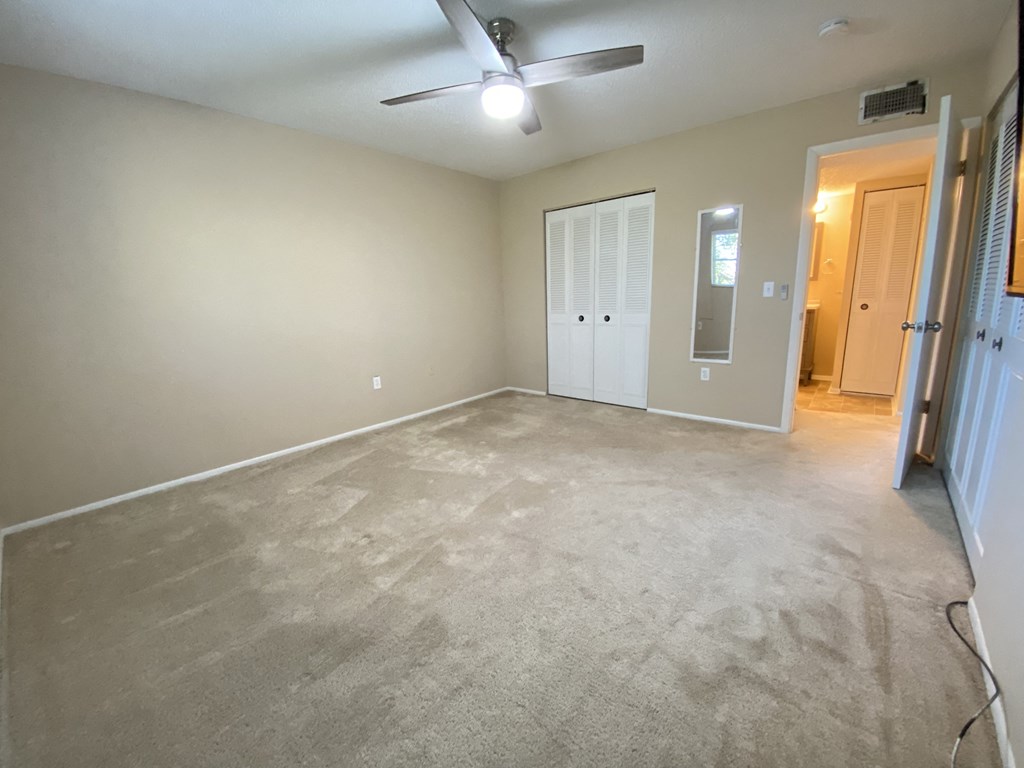 the living room of an empty house with a ceiling fan