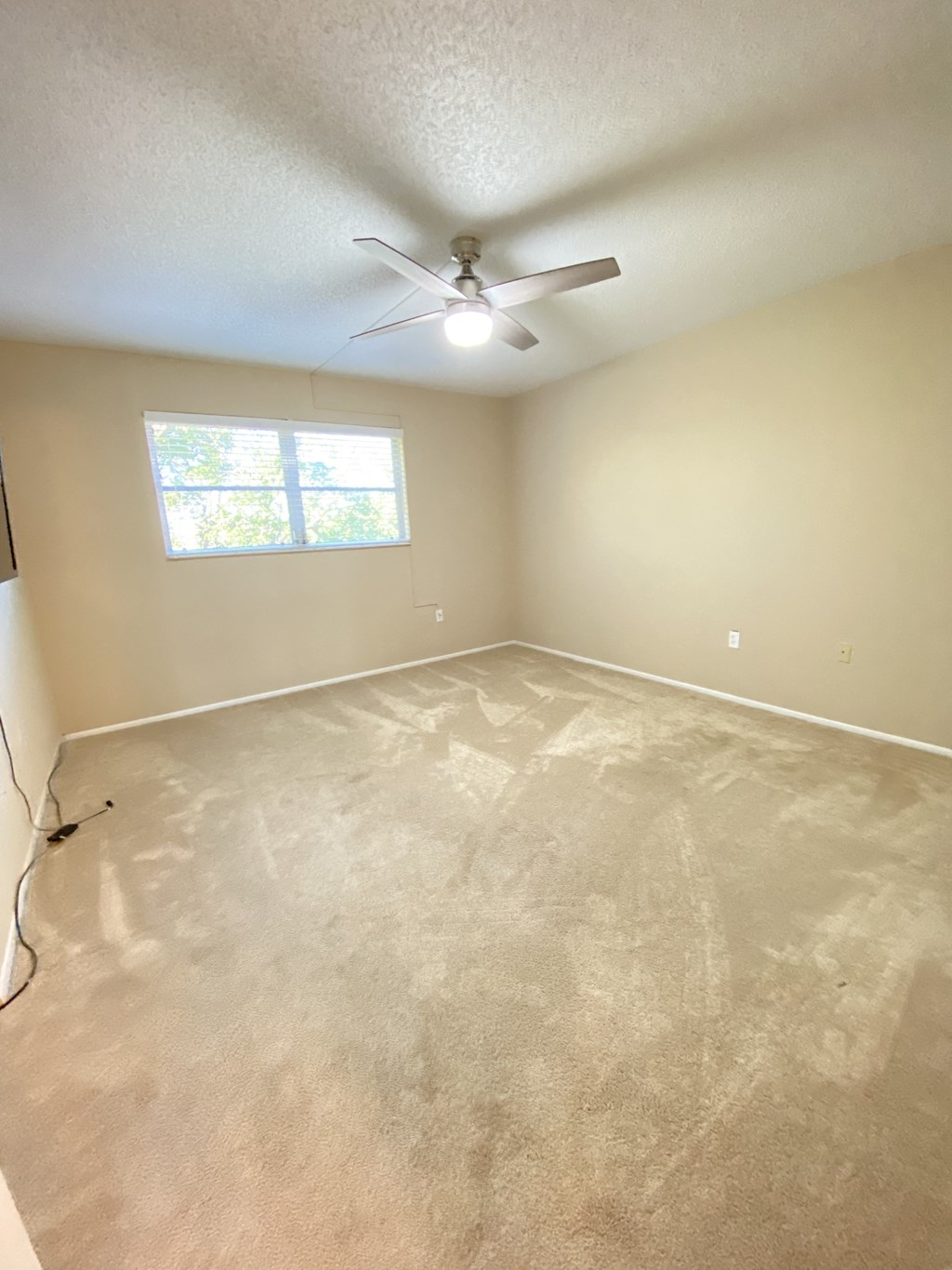 an empty room with a ceiling fan and a window