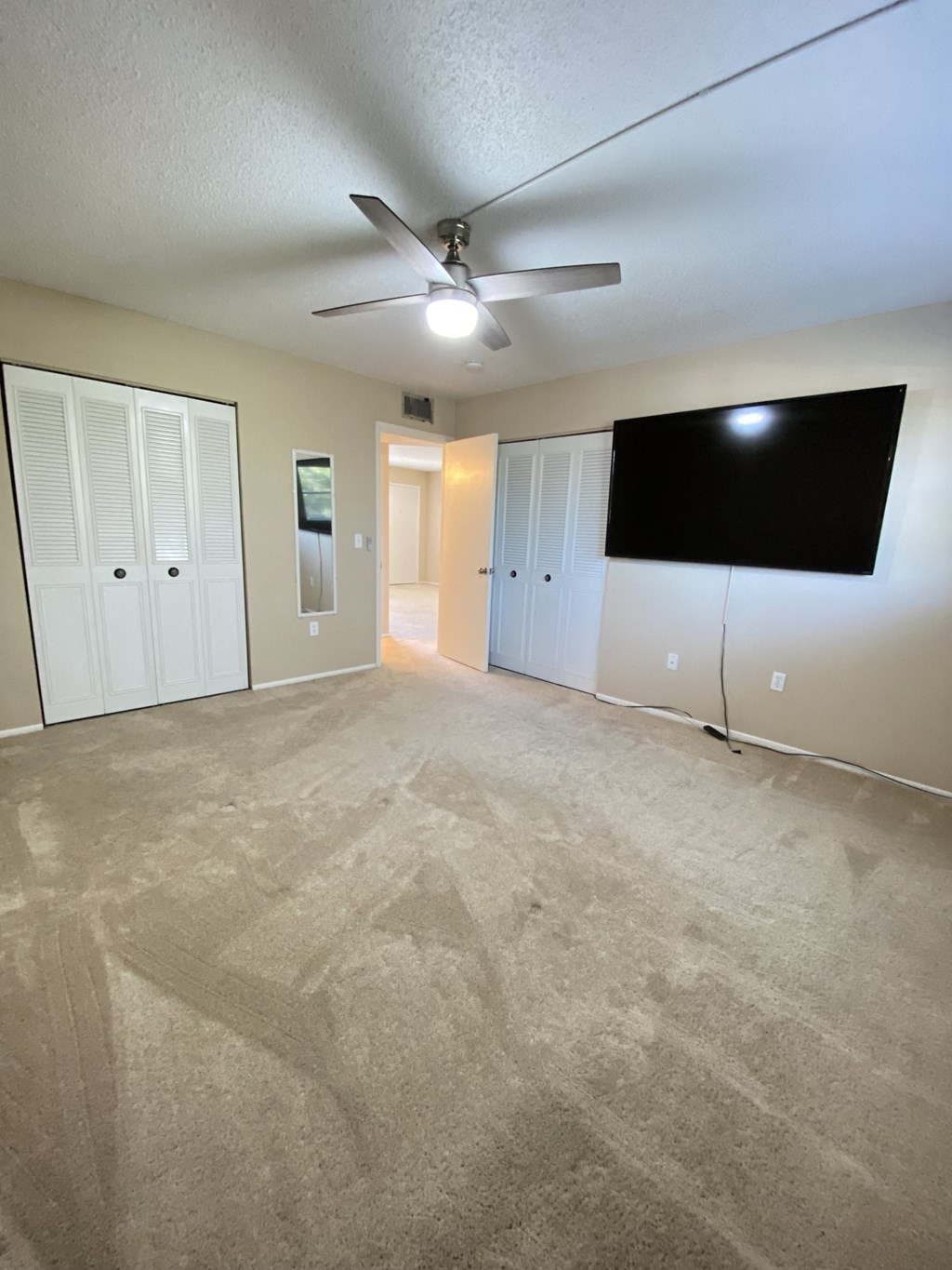 an empty living room with a ceiling fan and a tv
