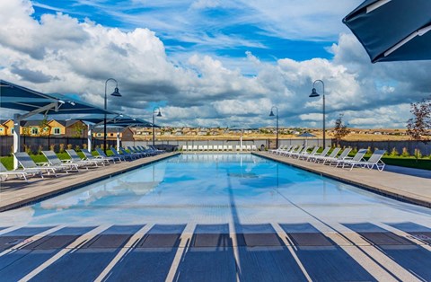 a large swimming pool with chairs around it and a cloudy sky