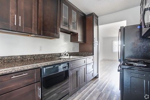 A kitchen with dark brown cabinets and black appliances.