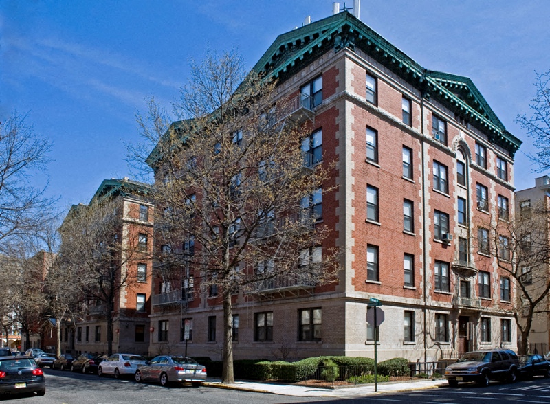 A red brick building with a green roof sits on a street corner.