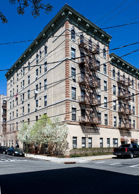 A large building with a brown brick facade and a green trim around the windows.