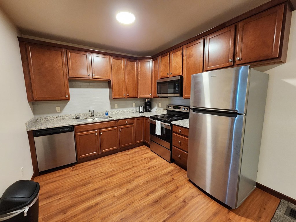 a kitchen with wood flooring and stainless steel appliances