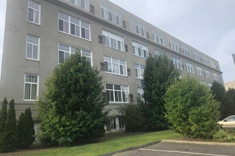 A grey building with trees in front.