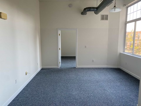 A room with a carpeted floor and a doorway leading to another room.