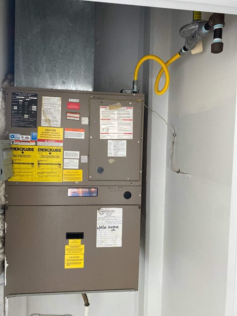A wall-mounted furnace with a yellow hose coming out of it.