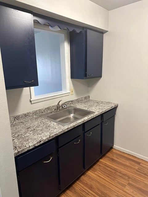 A kitchen with dark blue cabinets and a granite countertop.