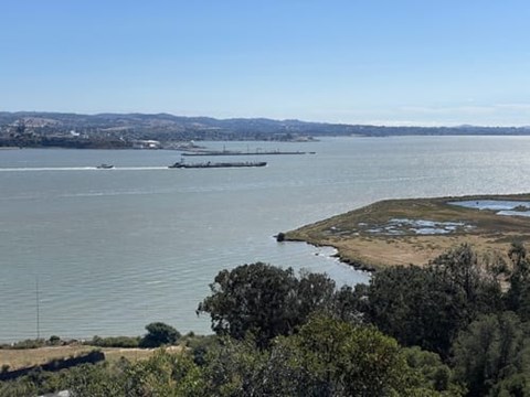A large body of water with a boat and a barge in it.