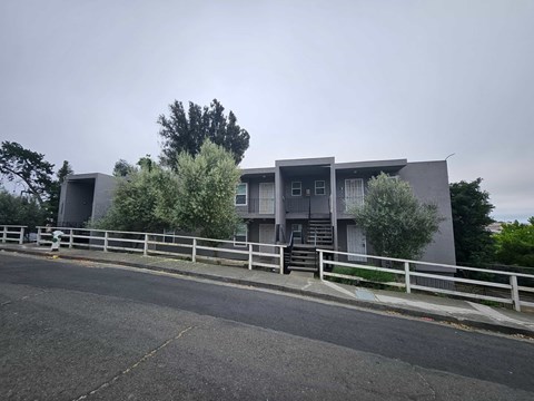 A grey building with a white fence in front of it.