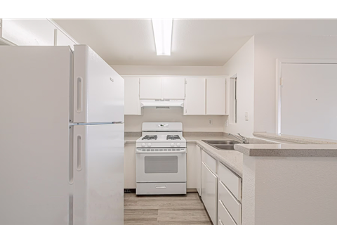 A white kitchen with a refrigerator, oven, and cabinets.