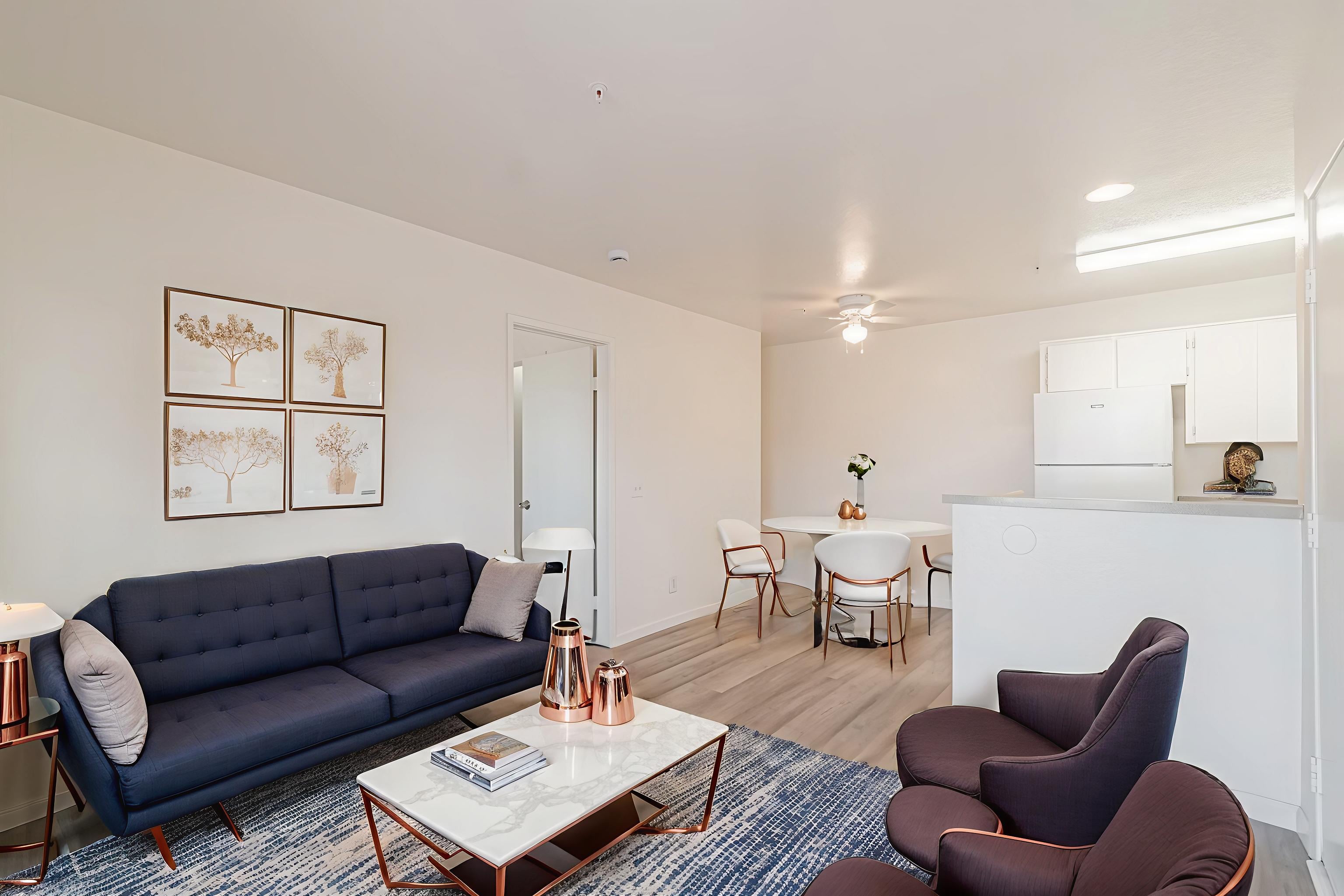 A living room with a blue sofa, a coffee table, and a dining table set up.
