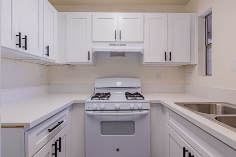 A white kitchen with a stove and cabinets.