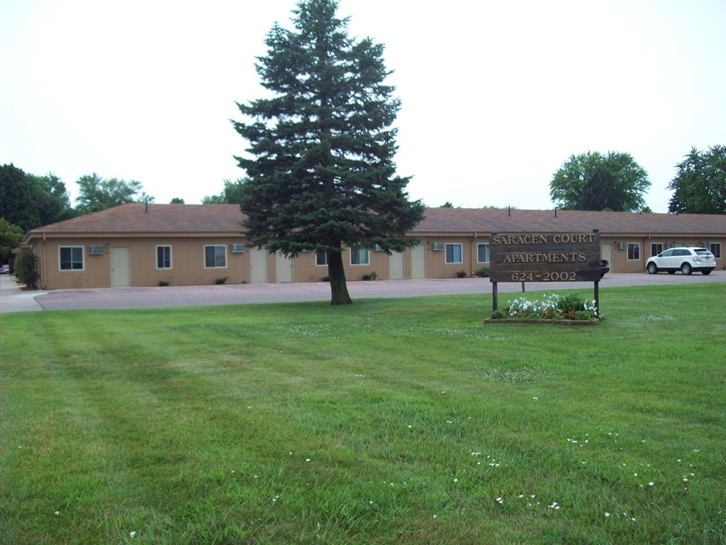 A sign in front of a building that says Saracen Court Apartments.