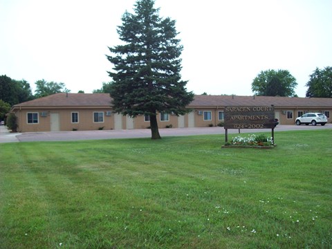 A sign in front of a building that says Saracen Court Apartments.