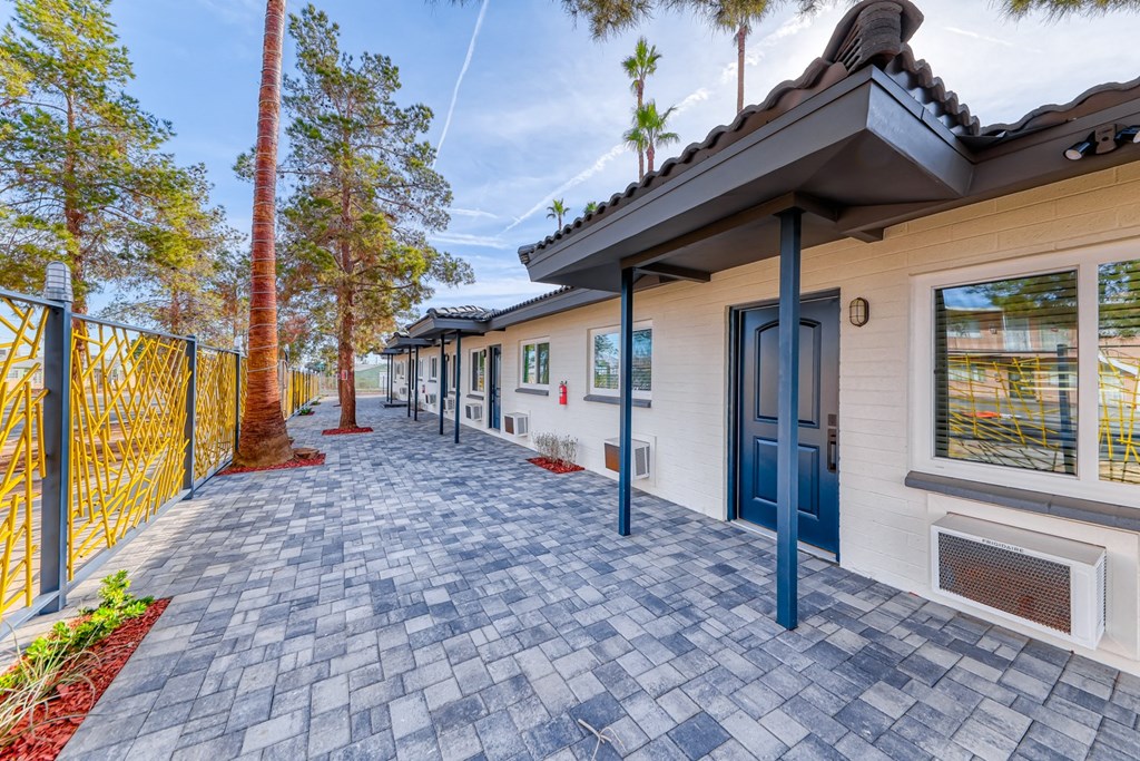 the entrance to a building with blue doors and a brick sidewalk