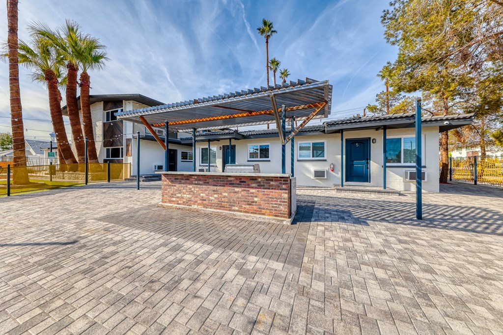 the front yard of a house with a brick wall and a porch with a grill