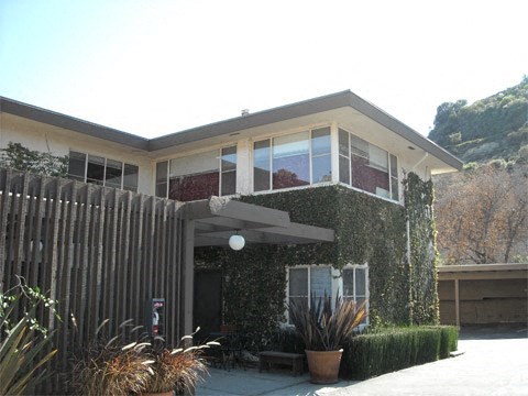 a house with a fence and plants in front of it